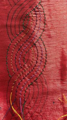 a red cloth with various colored threads on it