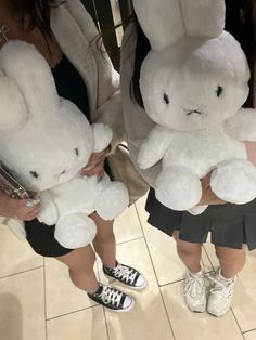 two women holding stuffed animals in their hands while standing next to each other on the floor