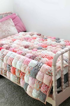 a bed with pink and white quilts on top of it next to a wall