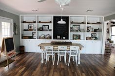 a dining room table and chairs in front of a chalkboard