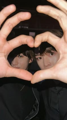 two people making the shape of a heart with their hands in front of each other