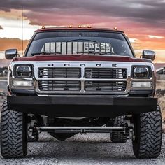 a red pick up truck parked on the side of a road in front of a cloudy sky