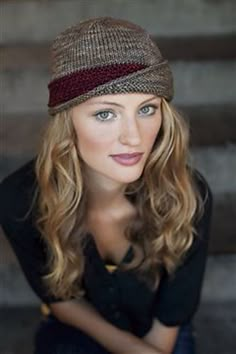 a woman with long hair wearing a brown and red hat on top of her head