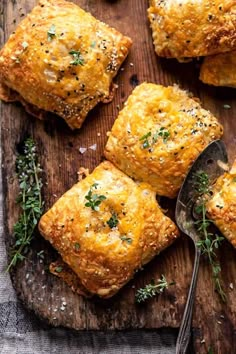 four square pastries on a wooden cutting board with a spoon and sprig of parsley