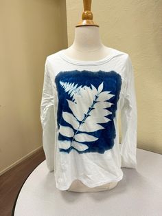 This botanical print T-shirt was made by using the cyanotype technique also knows as sun printing. Invented in 1842 by Sir John Herschel, cyanotype is a camera-less technique that utilizes UV (sunlight) to create prints. It is a photographic method that creates stunning white and Prussian blue images. I collect botanical items from Northern California and printed them onto 100% white cotton. All the prints are unique because of the nature of this process. You can never repeat the same pattern again. I use thrifted clothing to help reduce waste while offering unique, one-of-a-kind pieces. You will find that each piece is an original design and print, available in one size, style, and brand. I use the cyanotype process to combine my love of nature into beautifully printed pieces. I gather fl Cyanotype Shirt, Sun Printing, Blue Images, Cyanotype Process, Prussian Blue, Botanical Print, Herschel, Upcycle Clothes, Northern California