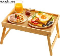 a wooden tray with food on it and a glass of orange juice next to it