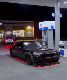 a black car parked in front of a gas station