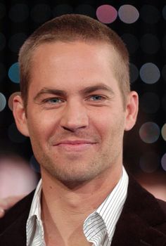 a close up of a person wearing a suit and smiling at the camera with blurry lights in the background