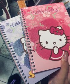 hello kitty notebooks are stacked on top of each other in a person's hand