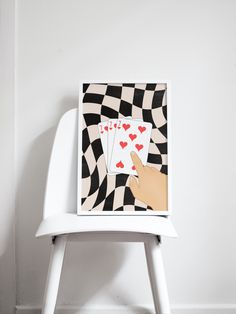 a white chair with a card on top of it next to a black and white checkered wall