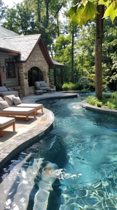 an outdoor swimming pool with chaise lounges next to it and trees in the background