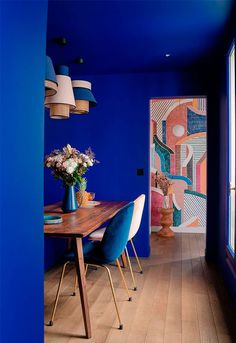 a dining room with blue walls and wooden floors