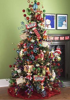 a decorated christmas tree in a living room with green walls and pictures on the wall