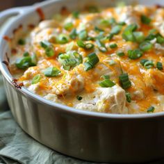 a casserole dish with chicken, cheese and green onion garnishes