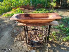 a wooden sink sitting on top of a metal stand in the dirt next to trees