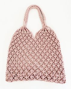 a crocheted pink bag on a white background with the handles pulled back to reveal an intricate pattern