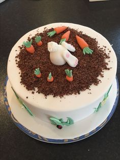 a cake decorated with carrots, grass and a bunny