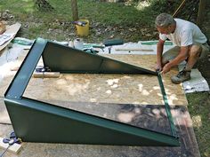 a man is working on some kind of structure in the woods with wood and plywood