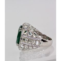 This is part of Chairish’s Fine Jewelry assortment.  Oval Emerald 12.25 Carat Diamond Surround 8.85 Carat Total Weight 21.10 Carat  This oval Emerald weights in at 12.25 carats and is a gorgeous Emerald Green with transparency. The Diamonds weigh in at 8.85 Carats and the mount is exceptional the Diamonds are VS1-VS2 and G-J in color. This is a bombe mount. The shoulders of the ring are embellished with baguette cut Diamonds in the center border with a perimeter of round cut Diamonds accents. Th Luxury Green Marquise Diamond Ring, Luxury Green Diamond Ring In Platinum, Luxury Diamond Cluster Ring With Gemstones, Luxury Cluster Ring With Round Cut Gemstone, Luxury Gia Certified Pear-shaped Wedding Ring, Luxury Gia Certified Jewelry For Evening, Luxury Emerald Ring With Diamond, Luxury Marquise Emerald Ring, Luxury Diamond White Diamond Ring For Formal Occasions