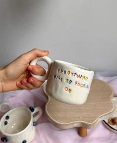 someone is holding a coffee mug on a table