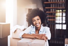 a woman sitting on top of a cardboard box in a room with boxes around her