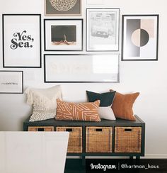 a black bench with baskets and pictures on the wall