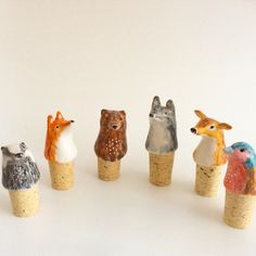 small animal figurines sitting in corks on a white surface, one is looking at the camera