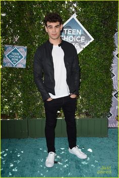 a young man standing in front of a green wall