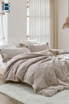 an unmade bed with fluffy blankets and pillows