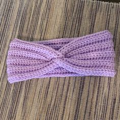 a purple knitted headband laying on top of a table