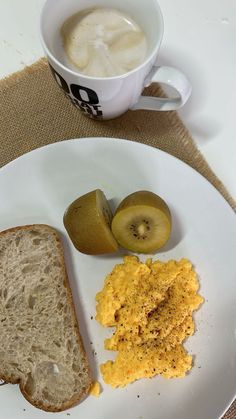 a white plate topped with an egg, toast and fruit next to a cup of coffee