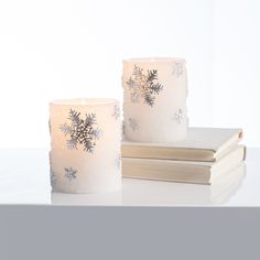 two snowflake candles sitting next to each other on top of a white table