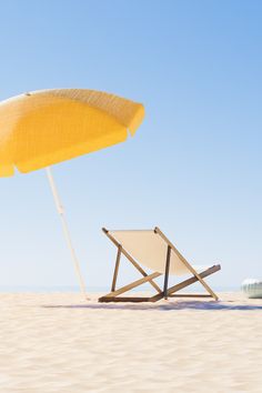 an umbrella and chair on the beach with blue skies in the backgrounnd