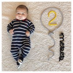 a baby is laying on the floor next to a balloon and number two sign that says 2