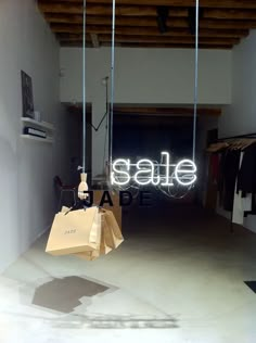 a shopping bag hanging from the ceiling in front of a neon sign that says sale