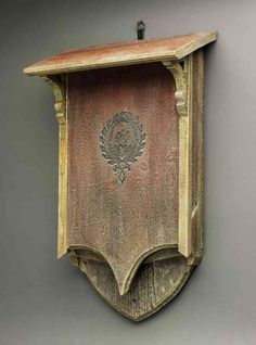 an old wooden clock hanging from the side of a wall with a plaque on it