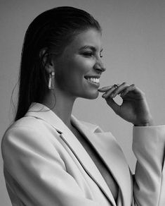 a black and white photo of a woman in a suit with her hand on her chin