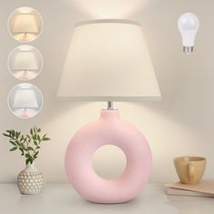 a pink lamp sitting on top of a table next to a white vase and pot