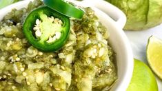 a white bowl filled with green food next to limes