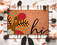 a door mat with the word hi on it next to pumpkins and pine cones