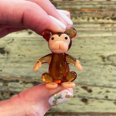 a hand holding a small glass monkey figurine