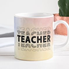 a coffee mug with the words teacher on it sitting next to a potted plant