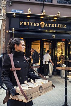 a woman is standing on the street with some food in her hand and looking at something