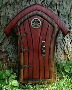 a small red door in the grass next to a tree