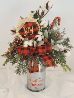 a christmas arrangement in a metal can with cotton, pine cones and candy canes