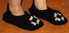 a woman's feet wearing black crocheted slippers with poodles on them