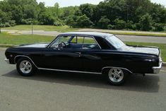 an old black car is parked on the side of the road