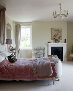 a bedroom with a bed, fireplace and chandelier in the middle of it