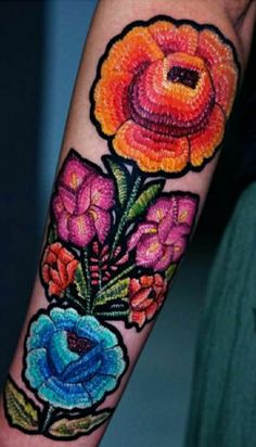 a colorful flower tattoo on the arm and wrist is shown with an orange, pink, blue and green flower