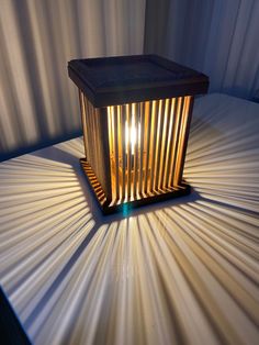 a lit candle sitting on top of a white sheet covered floor next to a curtain